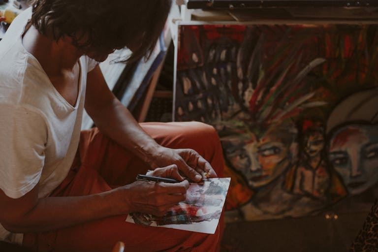 Artist immersed in sketching in a Paris studio, surrounded by colorful abstract paintings.