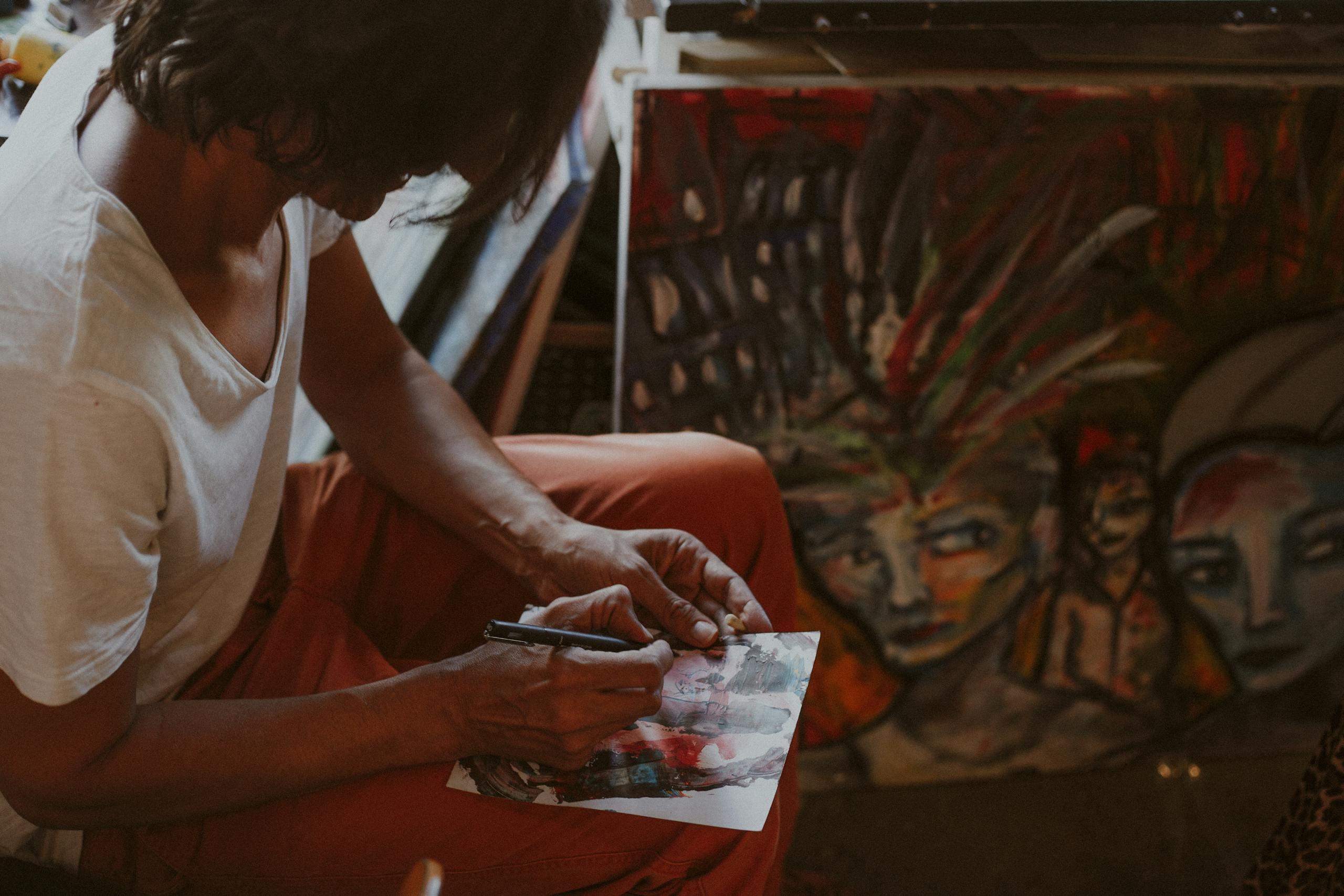 Artist immersed in sketching in a Paris studio, surrounded by colorful abstract paintings.
